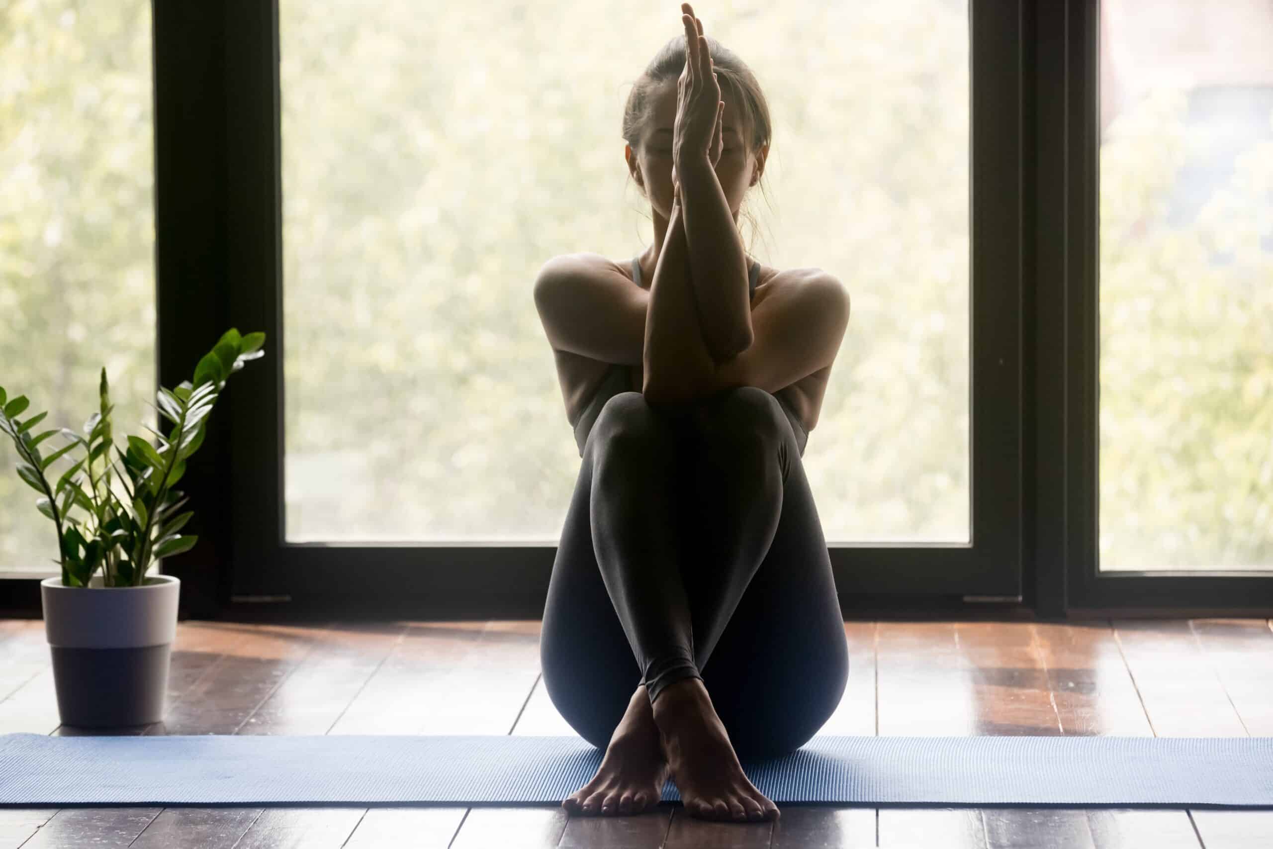 A woman doing yoga in front of a window.