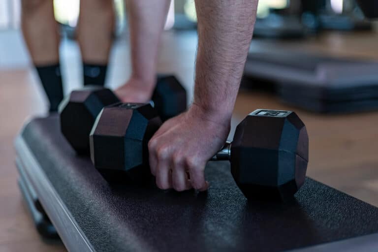 A person lifting a pair of dumbbells in a gym.