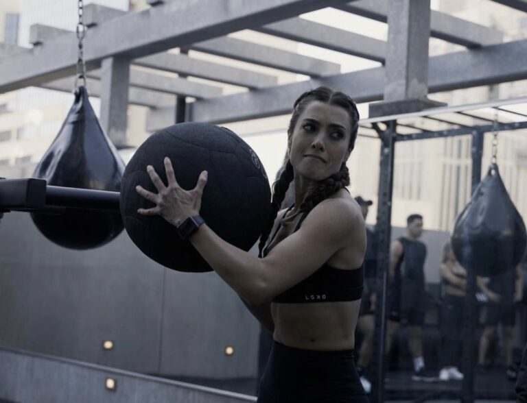 A woman is holding a weighted ball in a gym.
