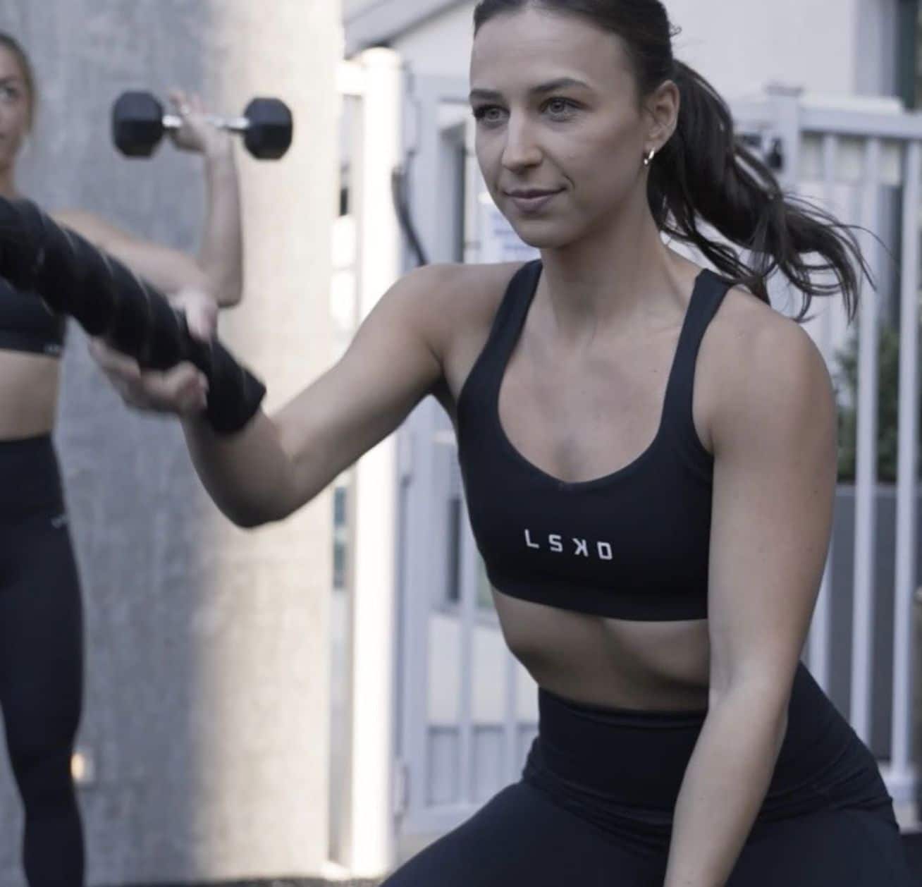 Two women working out with dumbbells in a gym.
