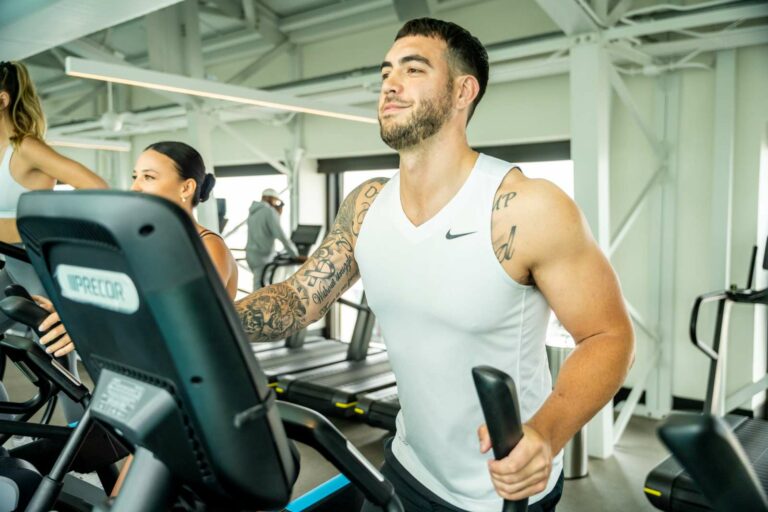 A man and woman on a treadmill in a gym.