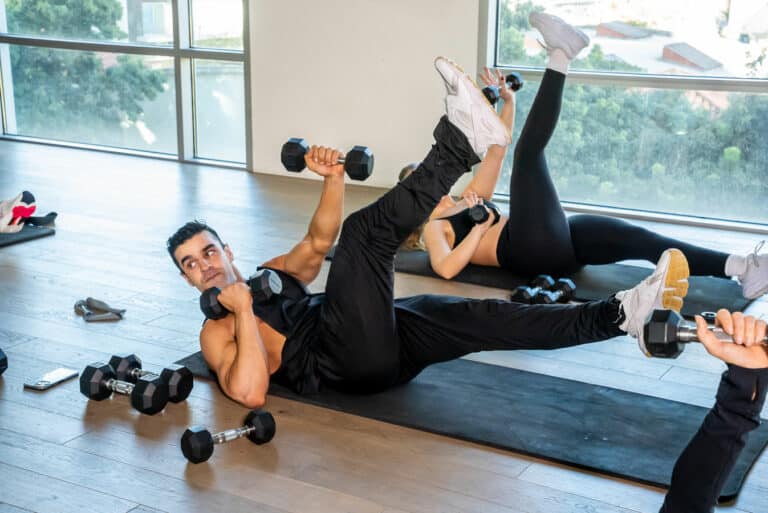 A group of people doing dumbbell exercises in a gym.