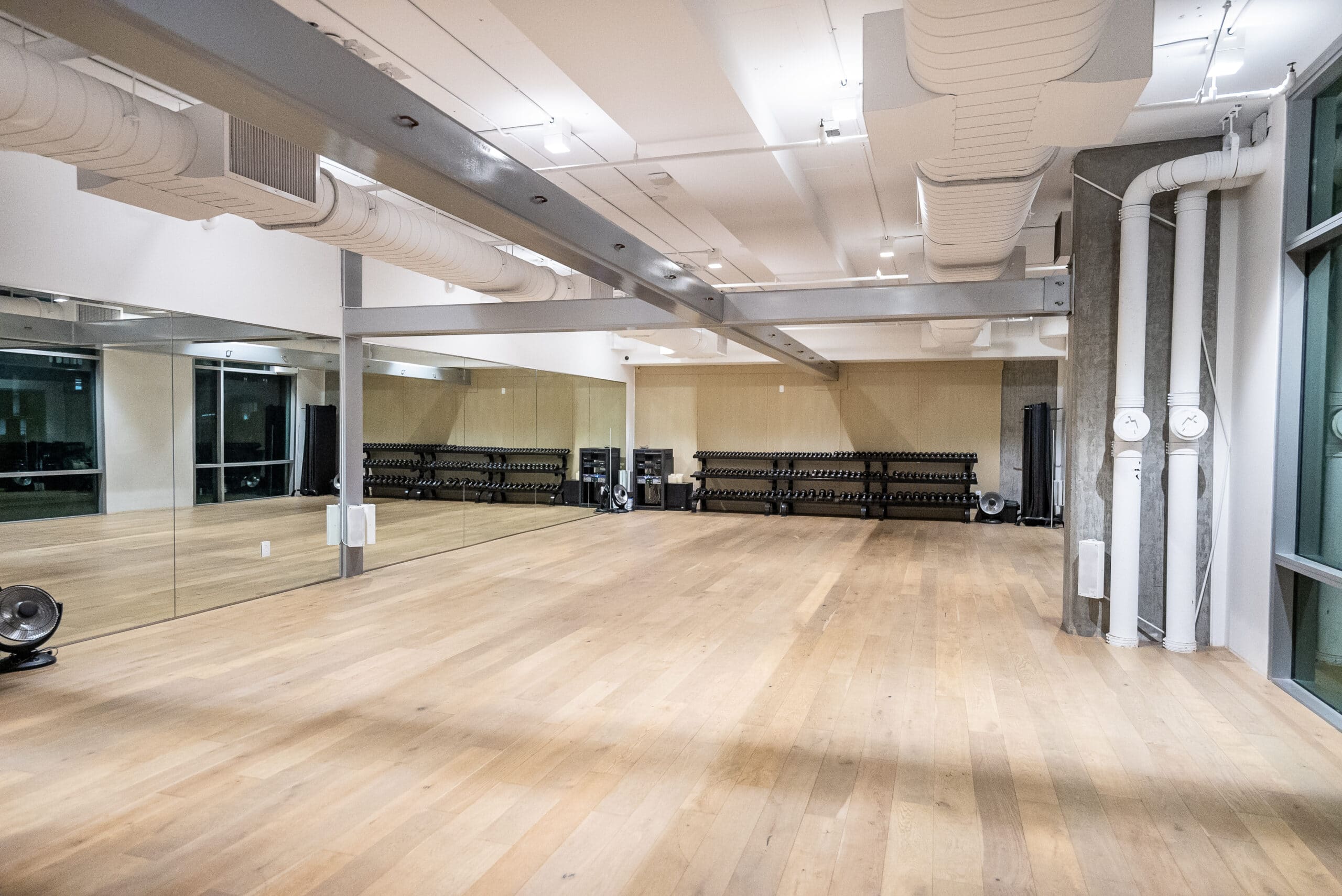 An empty dance studio with mirrors and wood floors.