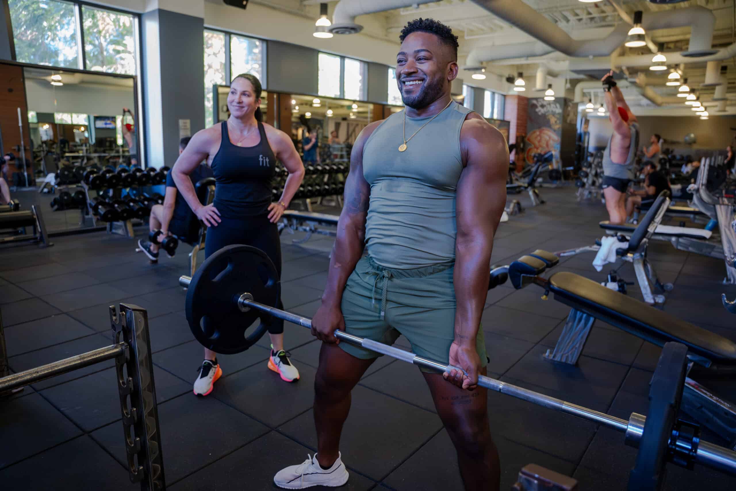 A man lifting a barbell in a gym.